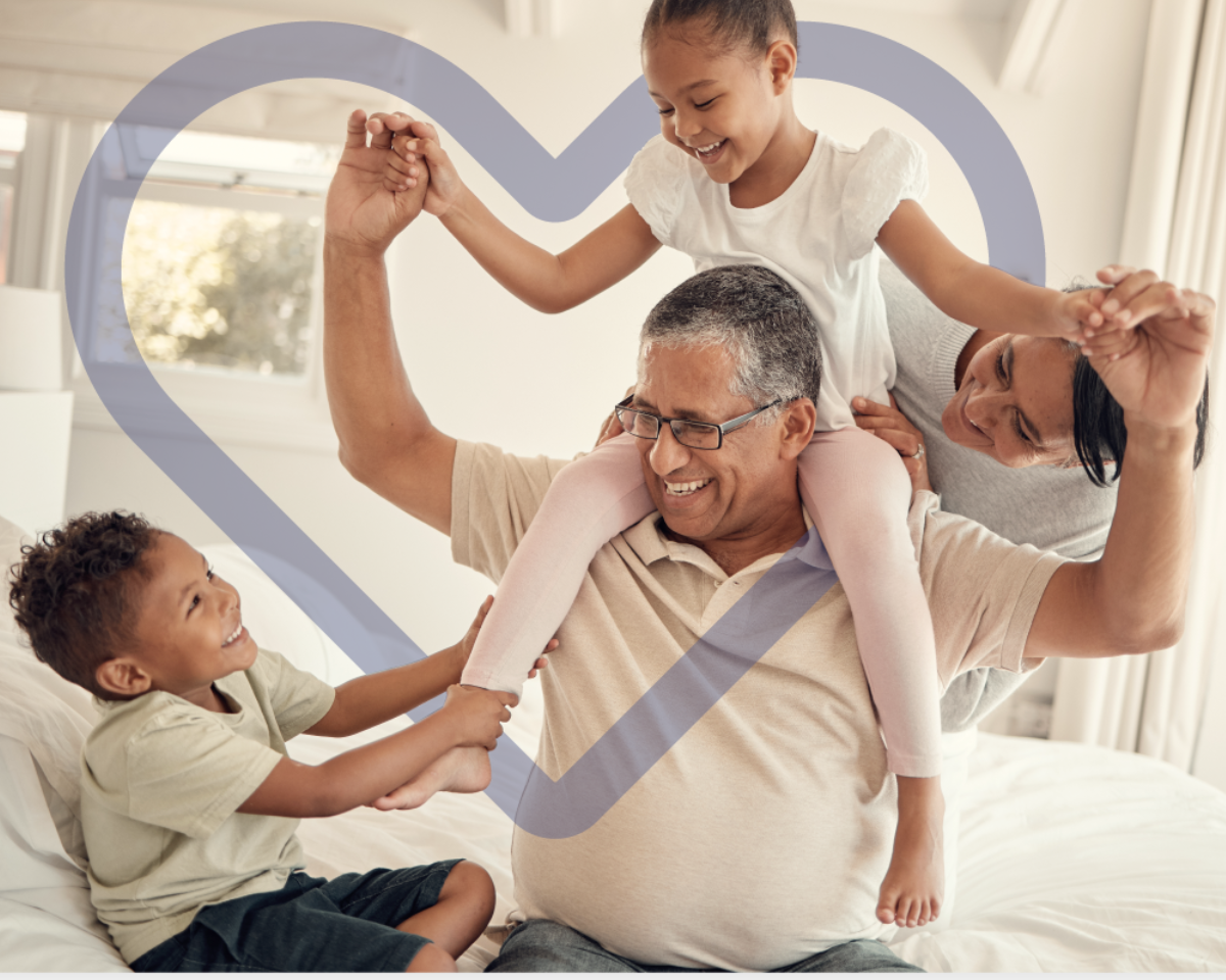 Smiling older man and woman playing with two young children at home.